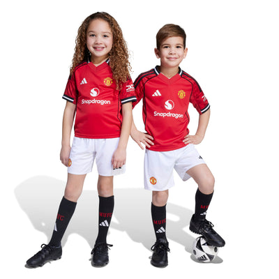Two children wearing Manchester United football jerseys on a white background